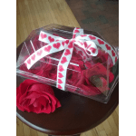 Clear gift box of red roses tied with a heart-patterned ribbon