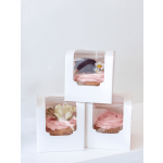 Three flower cupcakes in white boxes with pink and white frosting