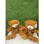 Two brown teddy bears with ribbons sitting on a round white surface