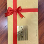 Gold gift box with a red ribbon and bow on a wooden floor