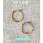 Pair of gold hoop earrings on a textured fabric background