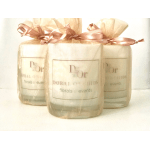 Three cream-colored candles wrapped in sheer organza bags with pink ribbons