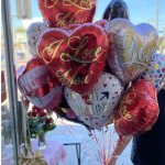 Cluster of heart-shaped balloons with love messages in red, white, and gold