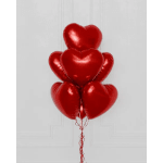 Cluster of red heart-shaped balloons against a white wall