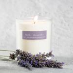 Lit white candle in a glass jar with dried lavender sprigs