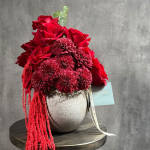 Red roses and burgundy mums in a silver vase with trailing red amaranthus