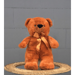 Orange teddy bear with a satin ribbon sitting on a woven mat