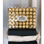 Box of Ferrero Rocher chocolates stacked on a dark box with rope trim
