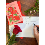 Valentine card with red flower illustration, a single red rose, and a hand writing inside an open card