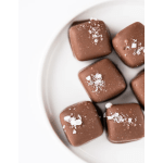 Square milk chocolates topped with coarse salt on a white plate