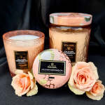Three scented candles with peach roses arranged in front