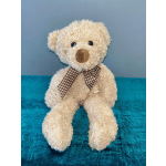 Cream teddy bear with a checkered ribbon sitting on a blue surface