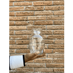 Clear glass vase held in a hand against a brick wall
