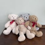 Four teddy bears with ribbon bows sitting on a table