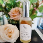Rose-shaped body oil bottle beside cream roses