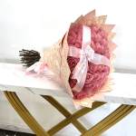 Pink rose bouquet wrapped in peach paper with a satin ribbon