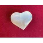 White heart-shaped stone on a red textured background