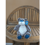 Plush teddy bear with blue paws and nose sitting on a wooden bench