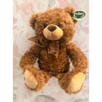 Brown teddy bear with a plaid bow tie against a floral background