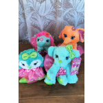 Four colorful plush animal toys with bows and dresses on a table