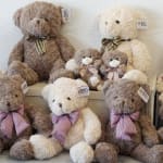 Assorted plush teddy bears with ribbon bows arranged on shelves