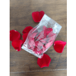Clear plastic bag with red rose petals on a wooden surface