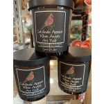 Three black-lidded candles with cardinal labels and memorial text