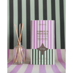 Reed diffuser in a glass bottle beside a striped product box