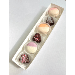 Long white tray with assorted round and heart-shaped pastel candies in paper cups
