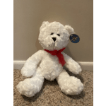 White teddy bear with a red ribbon sitting on carpet