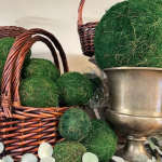 Wicker baskets filled with green moss balls beside a metal urn