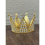 Gold jeweled crown with clear stones on a wooden surface