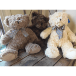 Three teddy bears with plaid bows sitting on a wooden surface