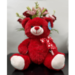 Red teddy bear with a bouquet of pink and red flowers behind it