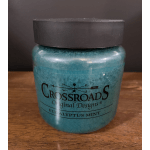 Blue-green scented candle in a black-lidded jar