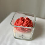 Red flower-shaped candle in a square glass container