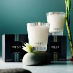 Two lit white candles with bamboo stalks and Nest New York boxes