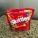 A red bag of Skittles candy on a countertop