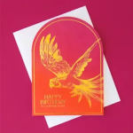 Birthday card with a gold bird illustration on a pink-orange background
