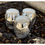 Three silver glass candles on a dark metal table