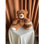 Brown teddy bear with a ribbon sitting on a draped table