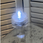 Blurred glowing blue light on a small round object beside window blinds