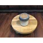 A candle jar sits on a small round wooden table