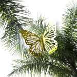Decorative butterfly ornament among palm fronds