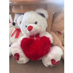 White teddy bear holding a red heart pillow