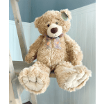 Large plush teddy bear with a plaid bow sitting on a wooden ladder