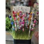 Colorful beaded keychains displayed in a black planter with faux grass