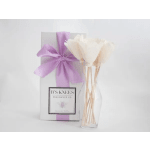 White flowers in a clear vase beside a lavender gift box with ribbon