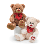 Two teddy bears with red bows and heart tags sitting on a white container