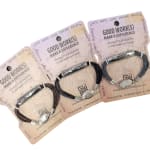 Three packaged cord bracelets with metal charms and printed cards